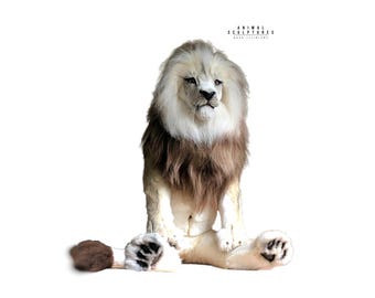 May include: A lifelike lion sculpture with a white and brown mane, sitting with its paws extended. The sculpture has a detailed face and fur texture. The text "ANIMAL SCULPTURES" is visible at the top.