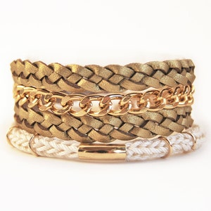 Può includere: Un braccialetto con catena dorata, una fascia in pelle intrecciata e una fascia in corda bianca.