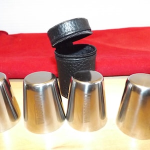 Peut inclure: Ensemble de quatre verres à shot en acier inoxydable avec un étui de transport en similicuir noir. Les verres sont coniques et portent l'inscription "Kikusuiwa". L'étui est cylindrique et zippé.