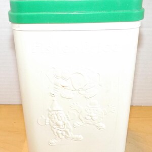 Puede incluir: Un contenedor de juguetes Fisher-Price vintage. El contenedor de plástico blanco tiene una tapa verde. En relieve en el lateral hay tres personajes de dibujos animados. El contenedor es rectangular y parece estar hecho de plástico duradero.