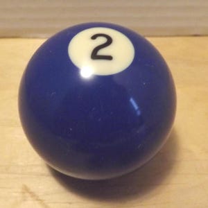 May include: A navy blue pool ball with a white circle showing the number 2 in black. The ball has a smooth, glossy surface. This is a standard size snooker ball.