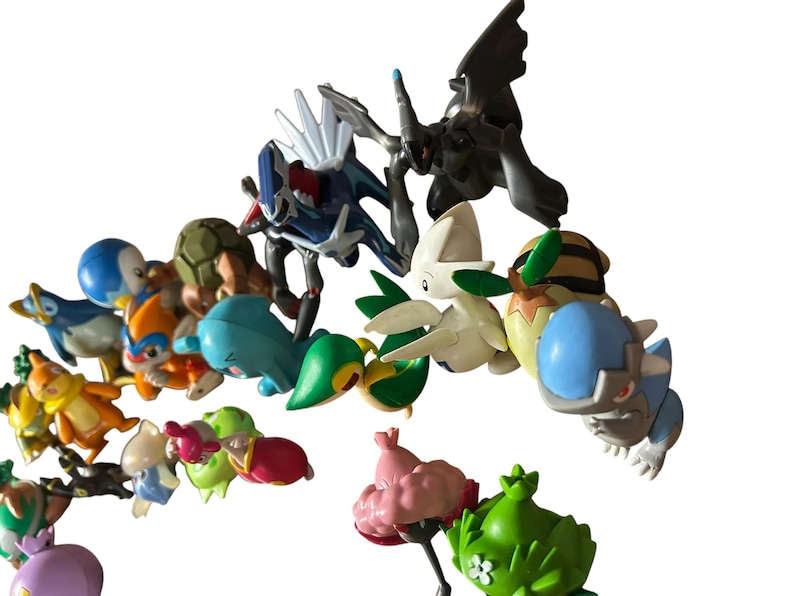 May include: A collection of various small plastic character figurines featuring diverse shapes and colors, including blue, green, pink, white, and brown. The figures depict stylized creatures with distinct features like wings, shells, and pointed ears.