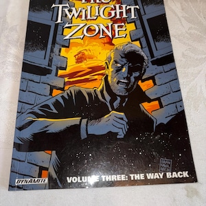 Może przedstawiać: Komiks zatytułowany "The Twilight Zone" autorstwa J. Michaela Straczynskiego. Okładka przedstawia mężczyznę z zaniepokojoną miną na tle płonącej sceny i ceglanych murów. Tom nosi tytuł "Volume Three: The Way Back."
