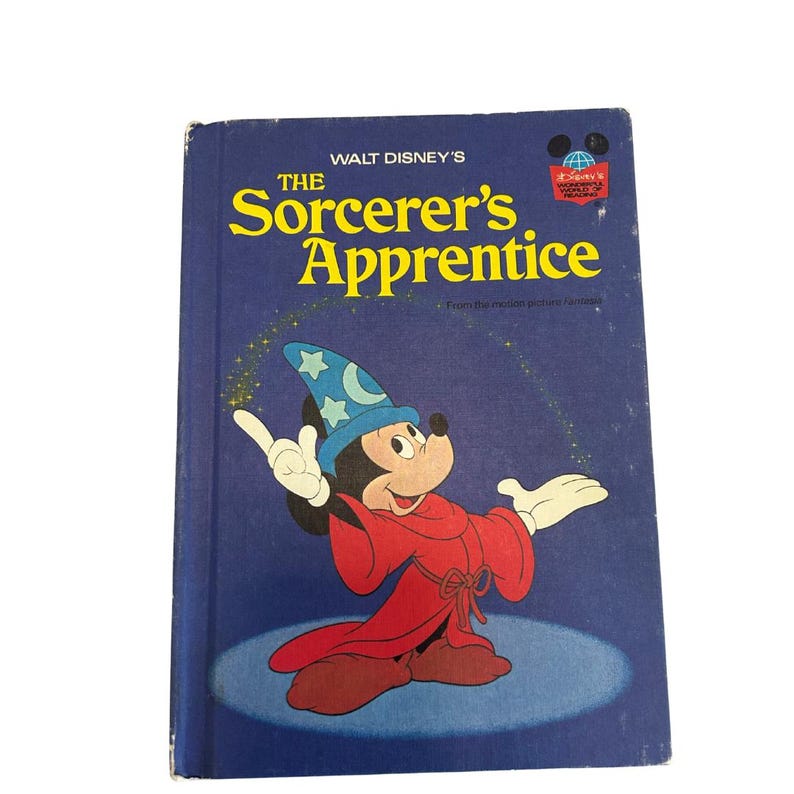 May include: A vintage hardcover book titled "The Sorcerer's Apprentice" featuring Mickey Mouse in a sorcerer's outfit. The cover is dark blue with yellow text and a cartoon illustration of Mickey Mouse.