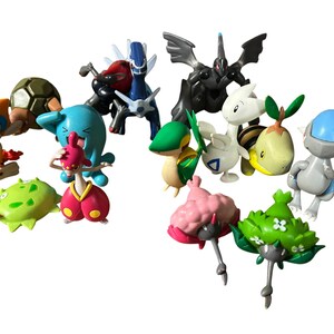 May include: A collection of various small plastic character figurines featuring diverse shapes and colors, including blue, green, pink, orange, and black creatures. The figures display distinct designs with wings, shells, and floral-like elements.