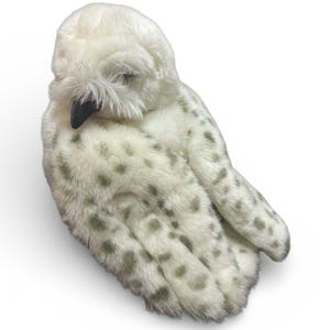Op de afbeelding: Een pluche sneeuwuil met een wit lichaam en grijs gevlekte vleugels. De uil heeft een zwarte snavel en kijkt naar beneden. Het speelgoed is gemaakt van zacht, pluizig materiaal.