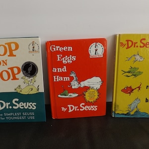 以下が含まれることがあります： 3冊のDr. Seussの子供向けの本。「Hop on Pop」、「Green Eggs and Ham」、「One Fish Two Fish Red Fish Blue Fish」。本には、イラストとテキストが描かれたカラフルな表紙があり、若い読者のためにデザインされています。