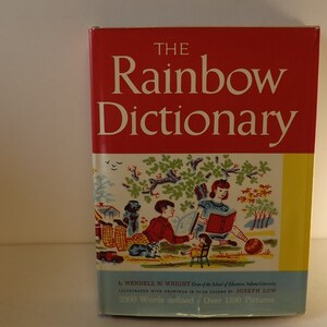 Puede incluir: Una copia vintage de "The Rainbow Dictionary" con una portada roja y el título en blanco. El libro presenta ilustraciones de niños leyendo y jugando. La portada también incluye el nombre del autor y el número de palabras definidas.