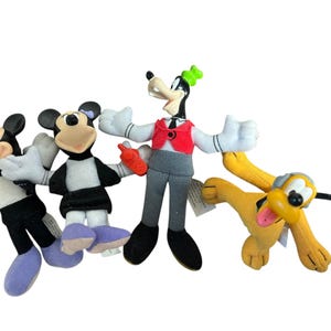 May include: A set of four plush character figures including Mickey Mouse in a black jacket, Minnie Mouse in a black dress with a purple bow, Goofy wearing a red vest and gray pants holding a red walkie-talkie, and a yellow Pluto dog figure.