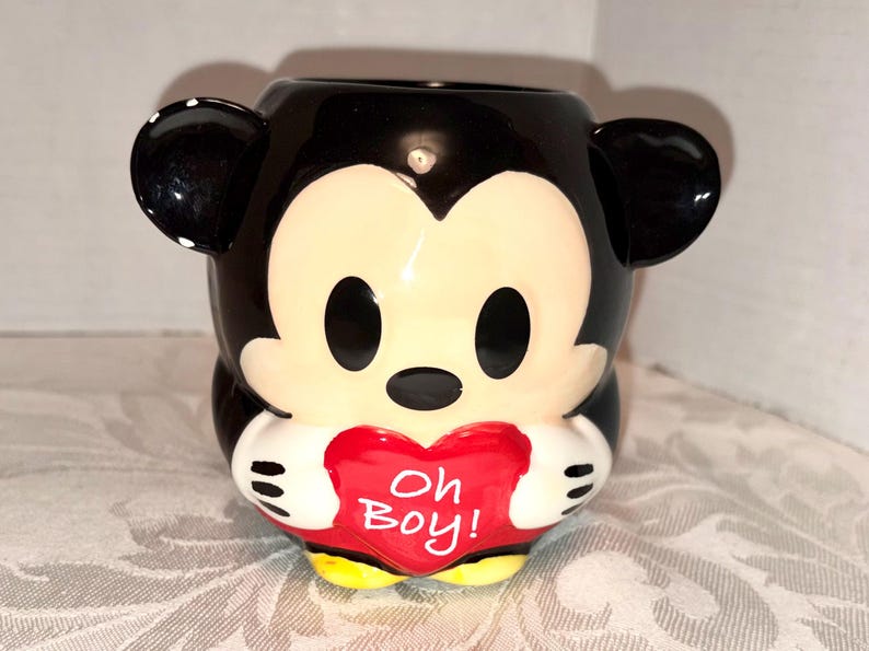 May include: A set of three ceramic mugs with a speckled, matte finish. The mugs are in shades of cream, light gray, and dark gray. Each mug has a simple, minimalist design and a rounded handle.