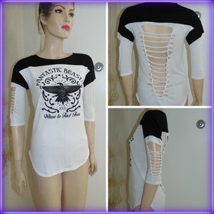 May include: A white and black baseball tee shirt with a graphic of a bird and the text "Fantastic Beasts and Where to Find Them". The shirt has distressed detailing on the sleeves and back.
