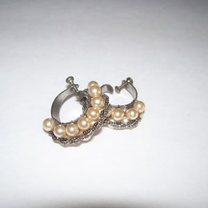 May include: A pair of silver hoop earrings with a row of faux pearls around each hoop.