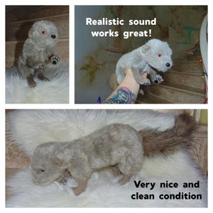 May include: A gray and brown plush toy wolf with red eyes. The wolf is in a sitting position with its tail curled behind it. The toy is in very good condition. "Realistic sound works great!" is written on the image.