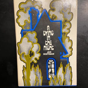 May include: Vintage paperback book cover with the title "A Dying in the Night" by Jan Roffman. The cover features a black house with blue trim, surrounded by stylized trees and smoke-like shapes in gold and gray.