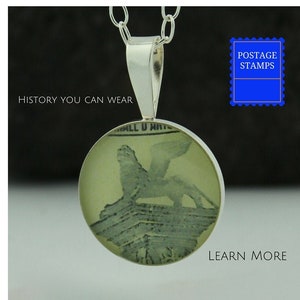 May include: A silver necklace with a round pendant featuring a vintage postage stamp image of a lion. The pendant is clear and shows the stamp's details. The necklace is on a black background with the text "HISTORY YOU CAN WEAR" and "LEARN MORE" in white.