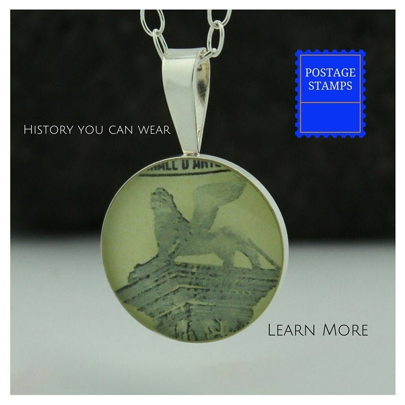 May include: A silver necklace with a round pendant featuring a vintage postage stamp image of a lion. The pendant is clear and shows the stamp's details. The necklace is on a black background with the text "HISTORY YOU CAN WEAR" and "LEARN MORE" in white.