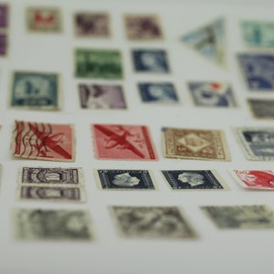 Puede incluir: Una colecci&oacute;n de sellos postales antiguos con varios dise&ntilde;os, incluyendo aviones, personas y patrones abstractos. Los sellos est&aacute;n dispuestos en filas sobre una superficie blanca.