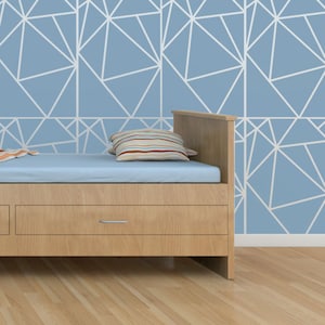 May include: A wooden bed frame with a light blue mattress and two striped pillows. The bed frame has a drawer underneath the mattress. The wall behind the bed is painted a light blue color and has a white geometric pattern.