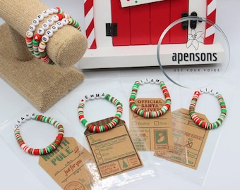 May include: A set of colorful Christmas bracelets with names spelled out in white letters. The bracelets are red, green, and white and have a festive holiday theme. Each bracelet is paired with a small card that says "Official Santa Delivery" and has a check box for "Naughty" and "Nice".