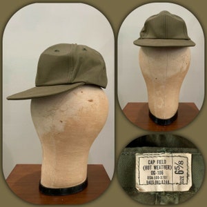 May include: A green military style field cap with a size tag that reads "CAP FIELD (HOT WEATHER) OG-106 DSA-100-3781 8405-082-5744 SIZE 65/8"