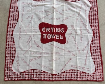 May include: A vintage white crying towel with a red border and a red center graphic that reads "CRYING TOWEL". The towel has handwritten phrases and the word "Democrats".