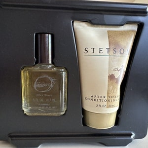 May include: A black gift box set containing a clear glass bottle of aftershave with a brown cap and a white tube of aftershave conditioner. The aftershave bottle has the text "After Shave 5 FL OZ 14.7 ml" and the conditioner tube has the text "STETSON AFTER SHAVE CONDITIONING 2 FL OZ 60 ml".