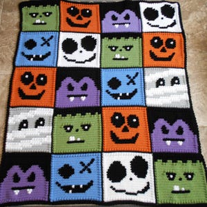 Puede incluir: Una manta de ganchillo de Halloween con una variedad de cuadrados coloridos que presentan diferentes caras de monstruos, incluyendo calabazas, fantasmas y vampiros.