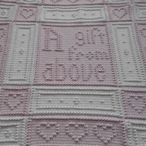 May include: A pink and white crocheted baby blanket with a heart pattern and the text "My 9 month adventure".