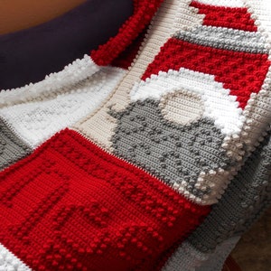 May include: A crocheted blanket with a red, white, and gray color scheme. The blanket is made with a textured stitch that creates a bumpy surface.