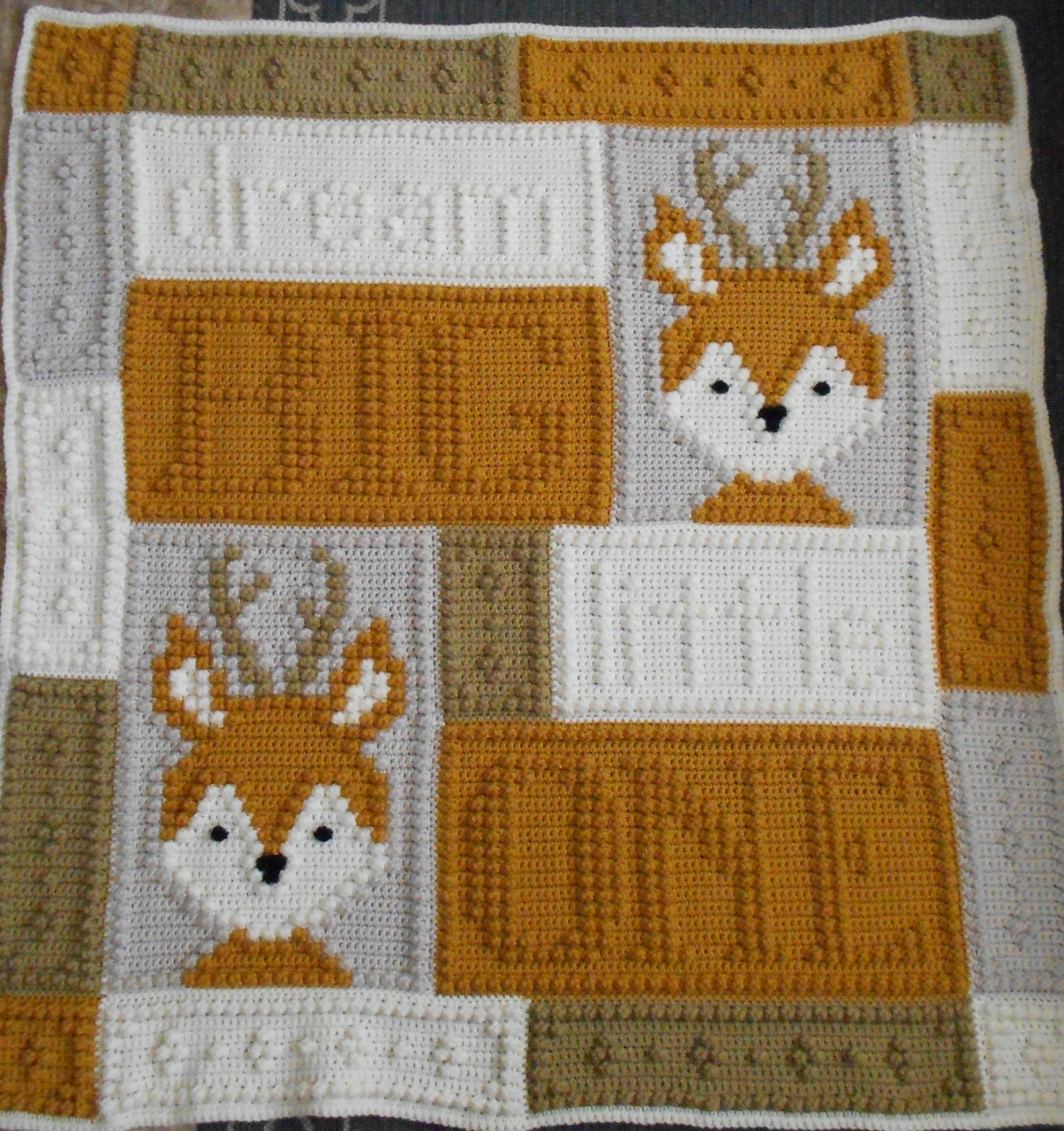 Crocheted baby blanket with foxes and the words Dream Big Little One in white, mustard, and olive blocks