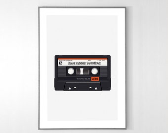 May include: A framed wall art print featuring a black cassette tape with orange accents. The label reads "BLADE RUNNER SOUNDTRACK" and "A60". The design includes technical details like "ACOUSTIC CASSETTE" and "Normal Bias 120µs EQ" printed on the tape.
