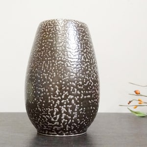 Könnte beinhalten: Eine gesprenkelte braune Keramikvase mit abgerundeter, ovaler Form.