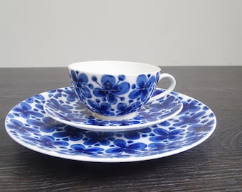Peut inclure: Un ensemble de trois assiettes en céramique blanche avec un motif floral bleu. Les assiettes sont empilées avec une tasse sur le dessus. La tasse est également blanche avec un motif floral bleu.