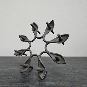 May include: A black cast iron candle holder shaped like a star with eight points. Each point has a small spike for holding a candle.
