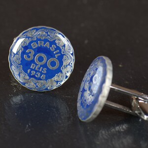 May include: A pair of cufflinks featuring a blue enamel coin with the text "BRASIL 300 REIS 1938" in silver lettering.