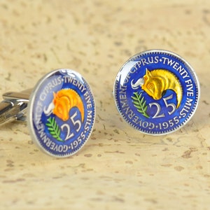 Peut inclure: Une paire de boutons de manchette repr&eacute;sentant une pi&egrave;ce de monnaie chypriote vintage de 1955 avec un fond bleu, un taureau dor&eacute; et le texte "GOVERNMENT OF CYPRUS TWENTY FIVE MILLS 1955-5 25".