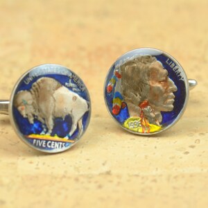 May include: A pair of cufflinks featuring a vintage American Indian Head nickel and a vintage Buffalo nickel. The coins are painted with blue, red, yellow, and white accents.