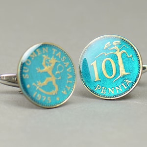 Pode incluir: Um par de bot&otilde;es de punho com moedas finlandesas antigas. As moedas s&atilde;o azuis com detalhes dourados e apresentam o texto "SUOMEN TASAVALTA 1975" e "10 PENNI&Auml;".