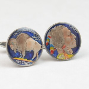 May include: A pair of cufflinks featuring a vintage American Indian Head nickel and a vintage Buffalo nickel. The coins are painted with blue, red, yellow, and white accents. The Indian Head nickel features the text "LIBERTY" and the Buffalo nickel features the text "UNITED STATES OF AMERICA" and "FIVE CENTS".