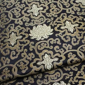 May include: Black fabric with a gold and white floral pattern. The fabric has a brocade texture.