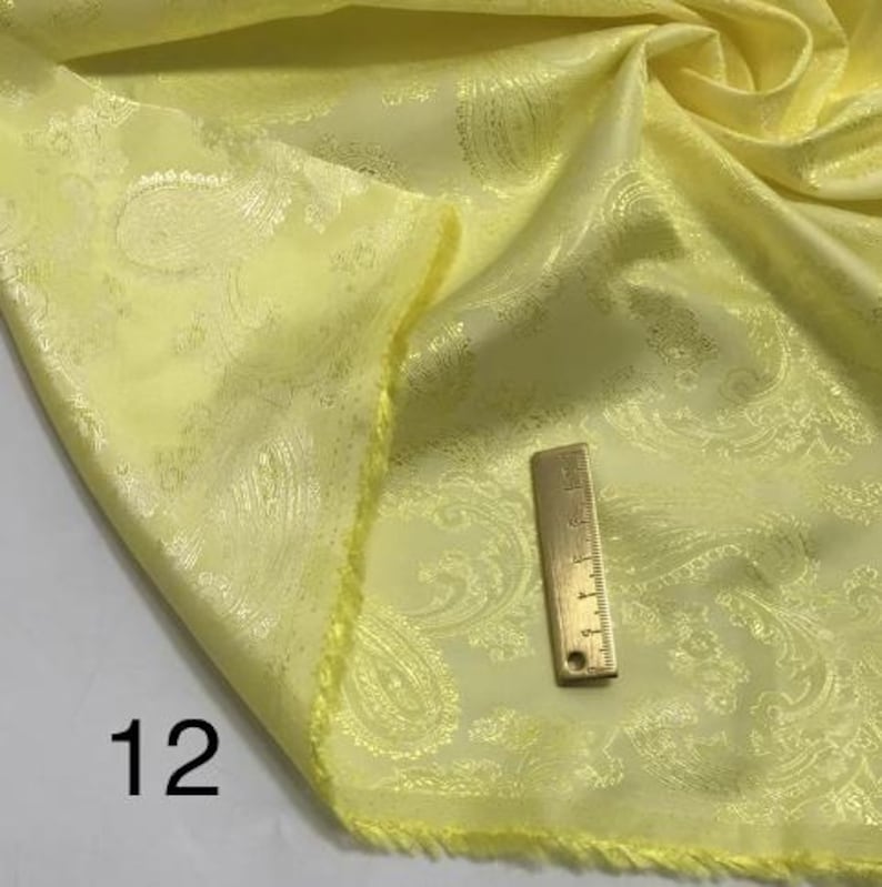 May include: A yellow paisley patterned fabric with a gold-coloured ruler measuring 30.5 cm.