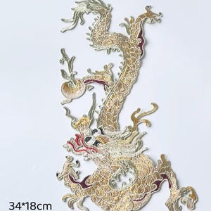 May include: Embroidered patch featuring a golden dragon design with red accents. The dragon is intricately detailed with scales and flowing features. The patch measures 34cm x 18cm, or approximately 13.4 inches by 7.1 inches.
