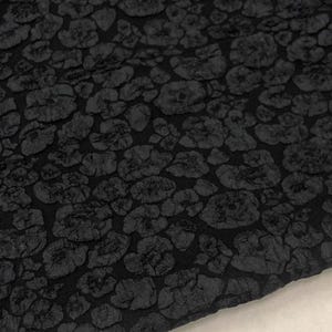 May include: Black fabric with a textured leopard print pattern.