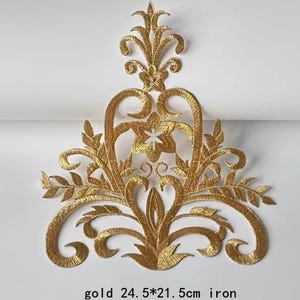 Peut inclure: Applique thermocollante dorée avec un motif floral. L'applique mesure 24,5 cm sur 21,5 cm.