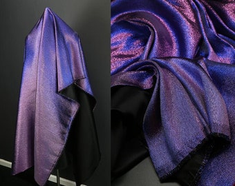 May include: A close-up of iridescent fabric in shades of purple and blue. The fabric has a subtle shimmer and a smooth texture.
