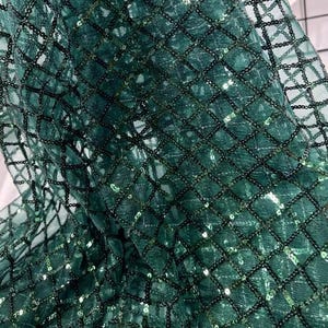 May include: Green sequined fabric with a diamond pattern. The sequins are small and closely spaced, creating a shimmering effect.