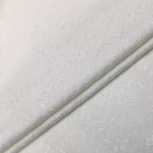 Puede incluir: Tela blanca con un patrón en relieve de diseños florales en espiral. La tela está doblada por la mitad, mostrando la textura del patrón.