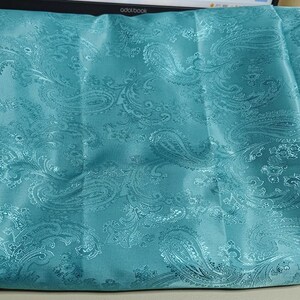 May include: Teal paisley patterned fabric with a satin finish.