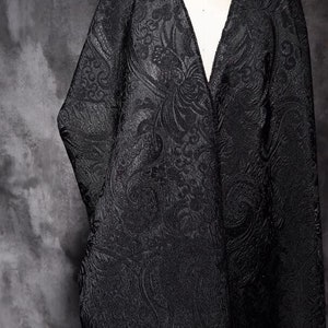 May include: Black fabric with a paisley pattern. The fabric is textured and has a slight sheen.