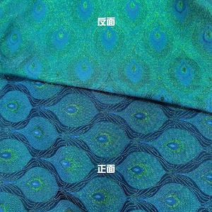 以下が含まれることがあります： 孔雀の羽根模様の生地のクローズアップ。生地は青と緑で、キラキラした仕上げになっています。画像の上半分には「反面」という文字が書かれており、下半分には「正面」という文字が書かれています。